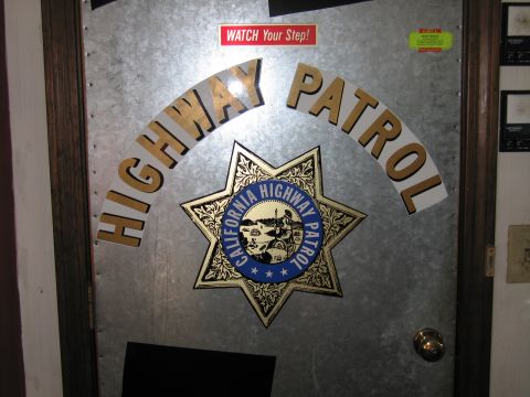 1991 Ford LTD Crown Victoria - Dimly lit galvanized metal door bearing arched HIGHWAY PATROL lettering and a California Highway Patrol star badge.