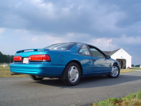1994 Ford Thunderbird - Blue 1994 Ford Thunderbird coupe seen from the rear, parked on a driveway with a garage in the background.