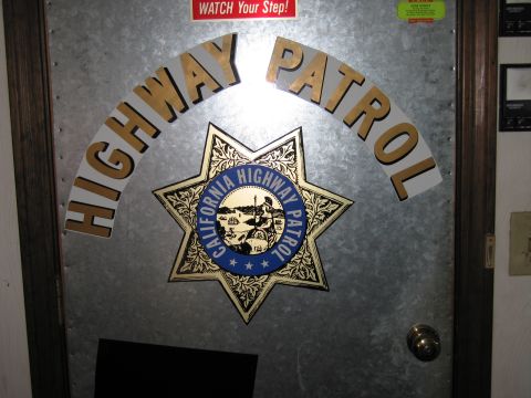 1991 Ford LTD Crown Victoria - Close view of a galvanized metal door with arched HIGHWAY PATROL lettering and a gold-and-blue California Highway Patrol star emblem.