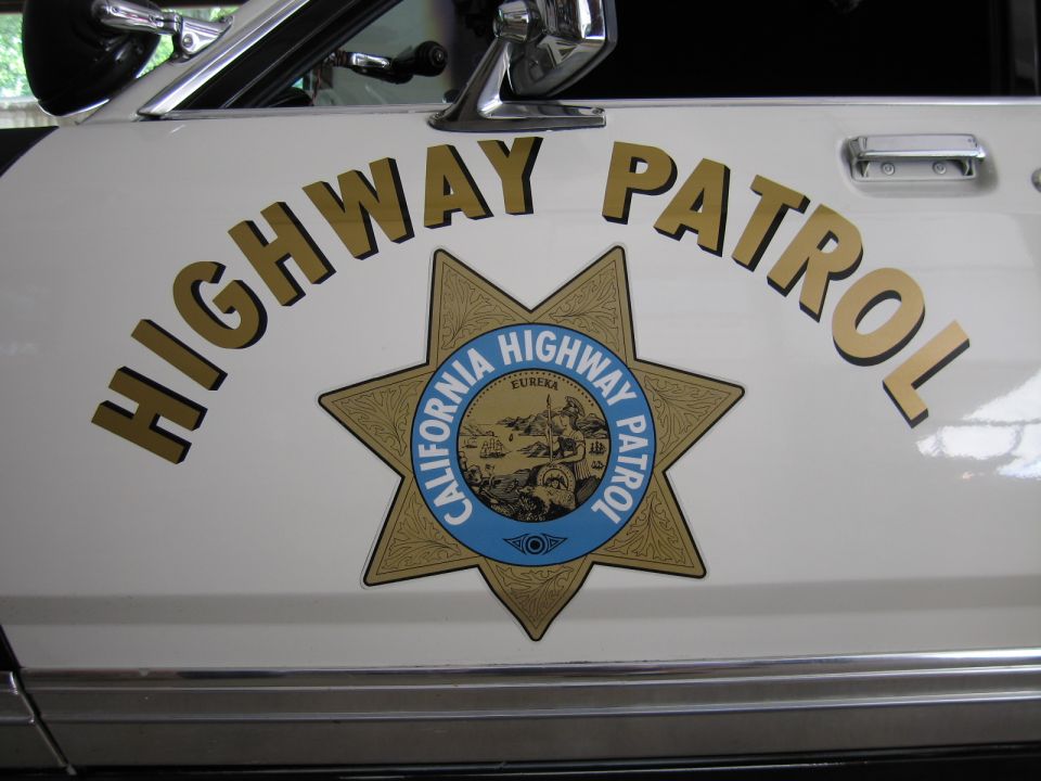 White police car door with arched HIGHWAY PATROL lettering and CHP star badge