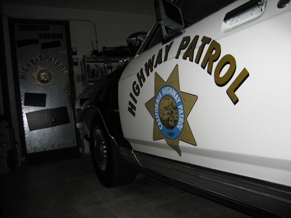 White police car door with CHP star and lettering beside matching emblem door