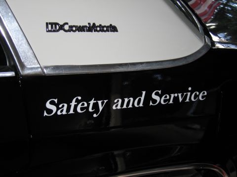 1991 Ford LTD Crown Victoria - Black police sedan rear quarter panel lettered Safety and Service in white, with an LTD Crown Victoria emblem above it.