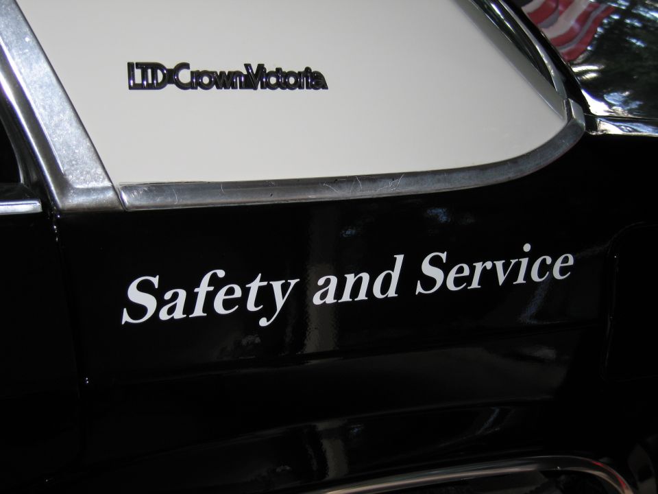 Black car quarter panel with white Safety and Service lettering and Crown Victoria badge
