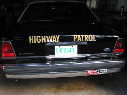 1991 Ford LTD Crown Victoria - Rear of a black Ford LTD Crown Victoria police car with yellow HIGHWAY PATROL lettering and a license plate reading CHP8849.