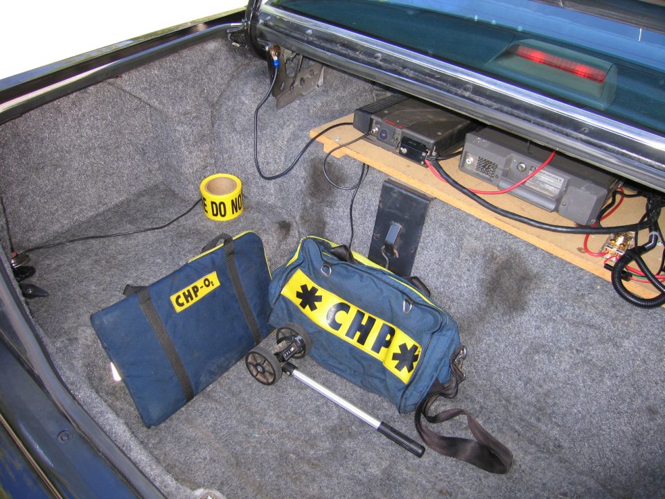 Open trunk with shelf-mounted radios, caution tape and yellow-and-navy CHP duffel bag