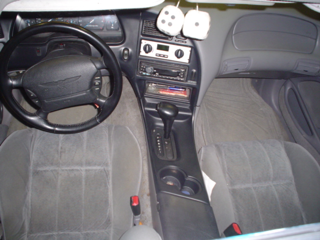 1994 Ford Thunderbird interior showing dashboard, steering wheel with bird emblem, center console with shifter, and grey seats