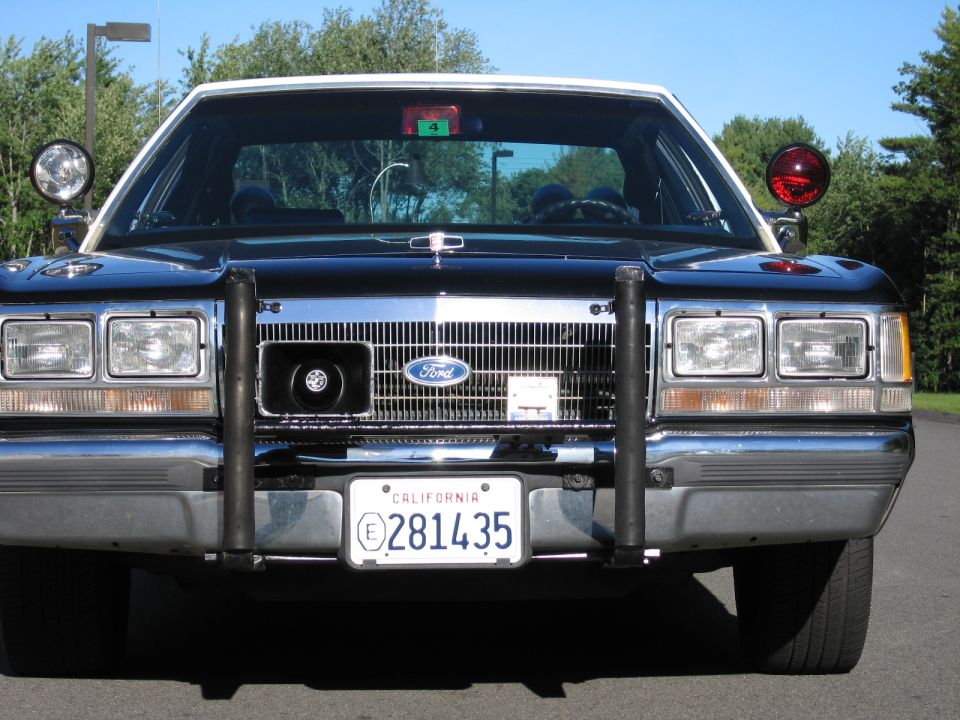Front view of dark Ford police sedan with brush guard and California plate