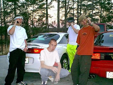 1992 Ford Probe - This photo shows a group of young men gathered around two cars, with one man in the foreground crouching.