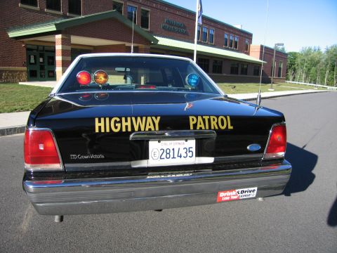 1991 Ford LTD Crown Victoria - Rear view of a black Ford LTD Crown Victoria police car with Highway Patrol lettering and California plate 281435 outside a brick school.