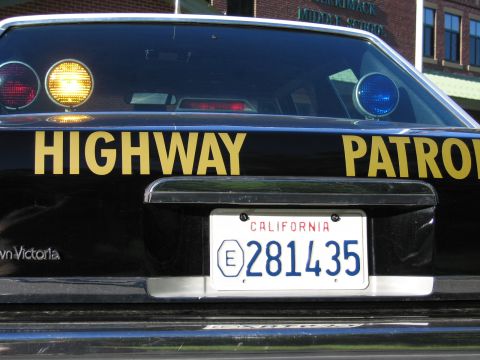 1991 Ford LTD Crown Victoria - Close rear view of a black Crown Victoria Highway Patrol car showing illuminated amber and blue roof lights and California plate 281435.