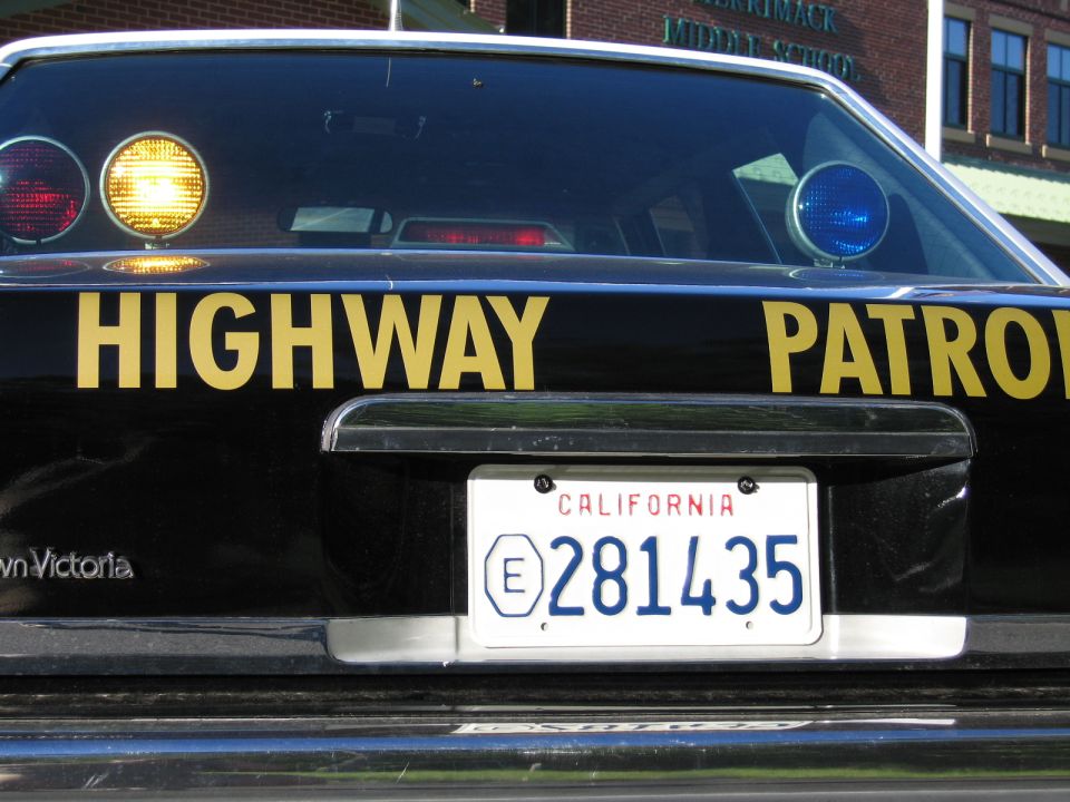 Close rear of black Crown Victoria Highway Patrol car with lit roof lights