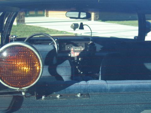 1991 Ford LTD Crown Victoria - View through a window into a police car interior with a mounted amber pursuit light, dash radio equipment and gray cloth bench seats.