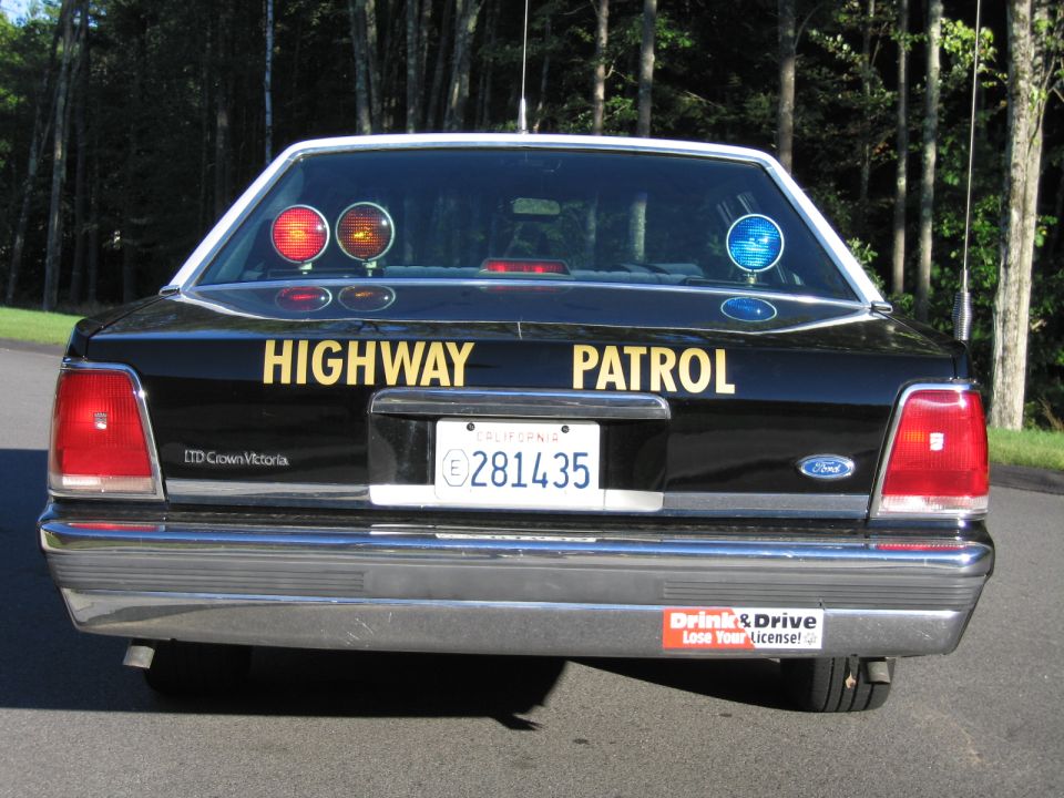 Rear three-quarter low view of black Ford LTD Crown Victoria highway patrol sedan