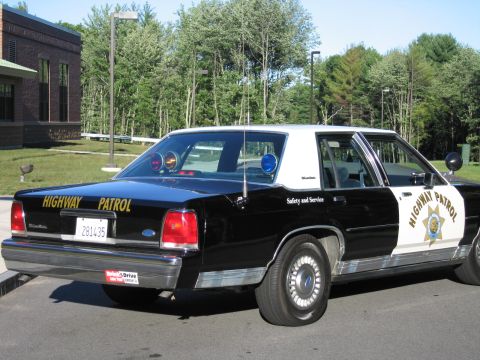 1991 Ford LTD Crown Victoria - Rear three-quarter view of a black-and-white Ford LTD Crown Victoria police car lettered HIGHWAY PATROL and Safety and Service.