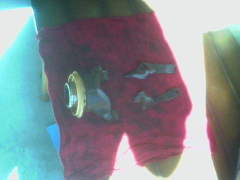 1987 Ford Bronco - Several metal parts, possibly from a vehicle's driveshaft, are resting on a red fabric surface.