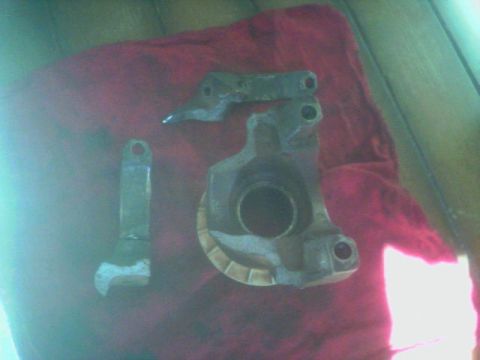1987 Ford Bronco - Two metal automotive parts are laid out on a red cloth, possibly for repair or inspection.