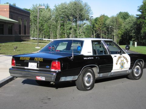 1991 Ford LTD Crown Victoria - Black-and-white Ford LTD Crown Victoria patrol car with a seven-point door star, HIGHWAY PATROL and Safety and Service lettering, parked by…