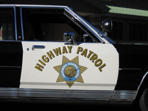 1991 Ford LTD Crown Victoria - Close-up of a patrol car door lettered HIGHWAY PATROL with a gold seven-point California Highway Patrol star and a spotlight above.