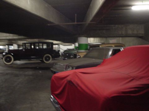 1968 Ford Mustang - Vintage automobiles are stored in a dimly lit parking structure, with one car prominently covered.