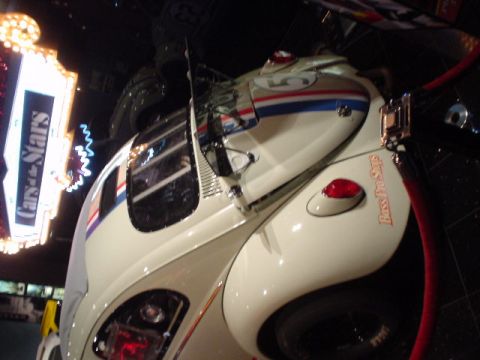 1968 Ford Mustang - A white Volkswagen Beetle, adorned with racing stripes and the number 5, is displayed indoors with a 'Cars of the Stars' sign in the backgr…