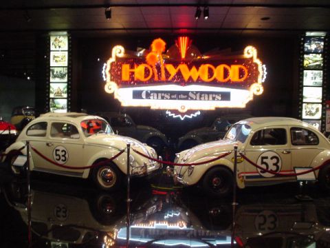 1968 Ford Mustang - Two iconic movie cars, likely Herbie the Love Bug, are displayed at the 'Hollywood Cars of the Stars' exhibit.
