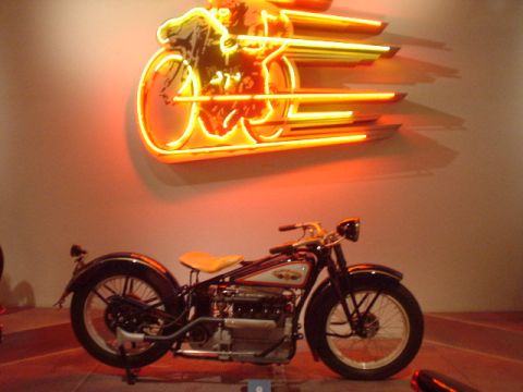 1968 Ford Mustang - A vintage motorcycle is displayed in front of a neon sign.