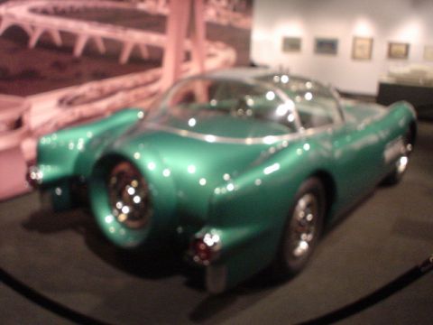 1968 Ford Mustang - A unique green concept car with a bubble canopy and distinctive rear-mounted spare tire is displayed in a museum setting.