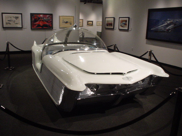 White concept car with a bubble canopy and chrome grille, displayed in a museum