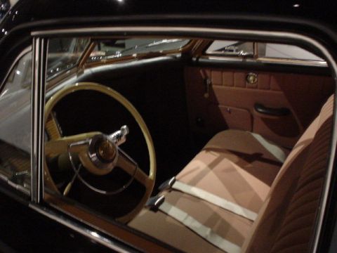 1968 Ford Mustang - The interior of a classic car features a tan steering wheel and brown seats with white seatbelts.