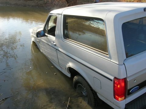 1994 Ford Bronco - White 1994 Ford Bronco stuck in shallow, muddy water.