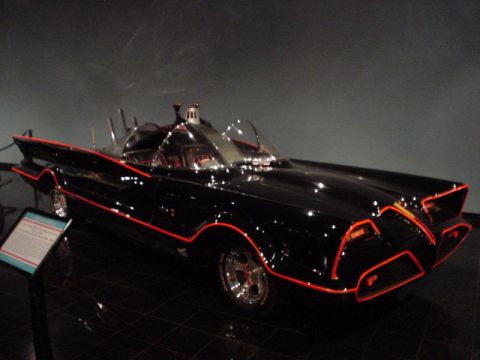 1968 Ford Mustang - A black custom car with red trim is displayed indoors, with a plaque to its left.
