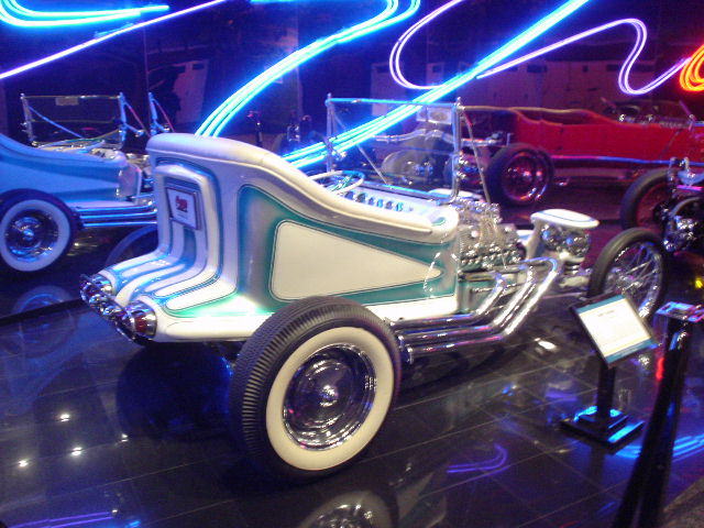 White and teal custom hot rod, 3q-front view, with exposed engine and neon lights