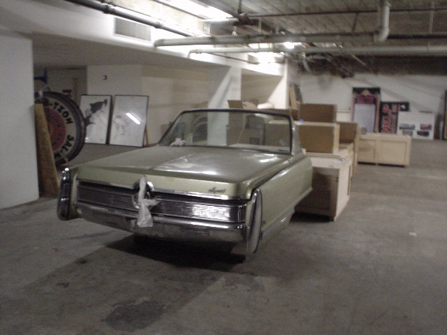 1967 Chrysler Imperial convertible parked indoors with boxes stacked behind it