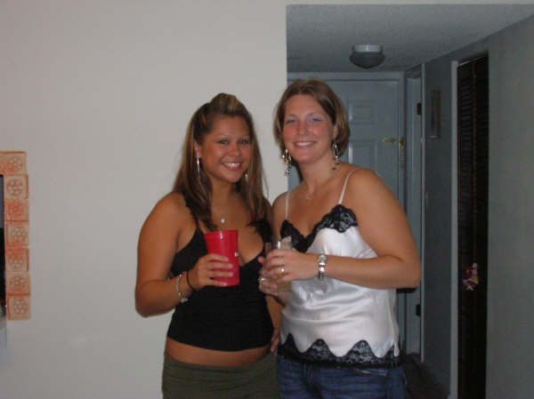 Two women smiling and holding drinks indoors