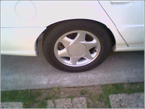 1993 Ford Taurus - Rear wheel and fender detail of a white 1993 Ford Taurus.