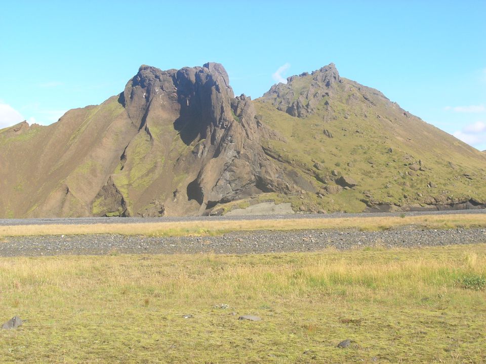 Rocky mountains and grassy plains under a blue sky