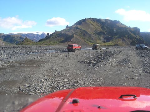 2001 Jeep Wrangler - Multiple SUVs navigate a , rocky terrain under a bright blue sky with distant mountains.