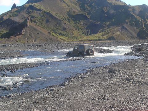 2001 Jeep Wrangler - A Jeep TJ navigates a shallow river in a , mountainous landscape.