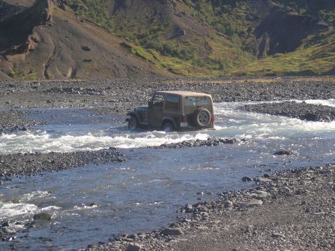 2001 Jeep Wrangler - A Jeep Wrangler navigates a shallow, rocky riverbed in a mountainous, arid landscape.