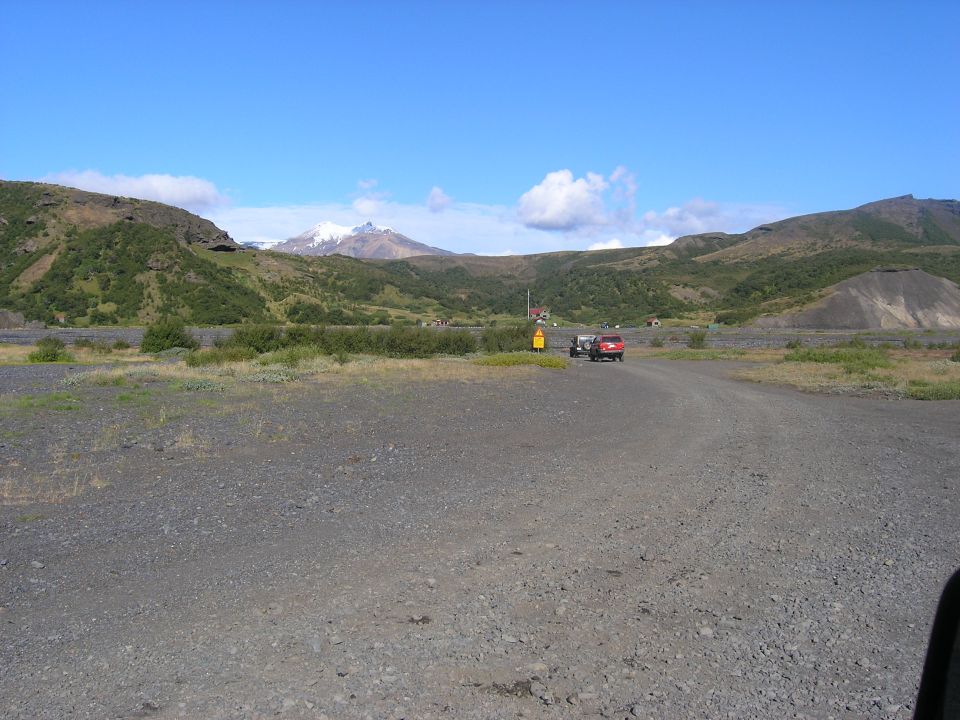 Red SUV towing a trailer on a gravel road with mountains in the background