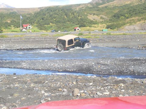 2001 Jeep Wrangler - A Jeep TJ navigates a shallow riverbed in a mountainous, rural landscape.