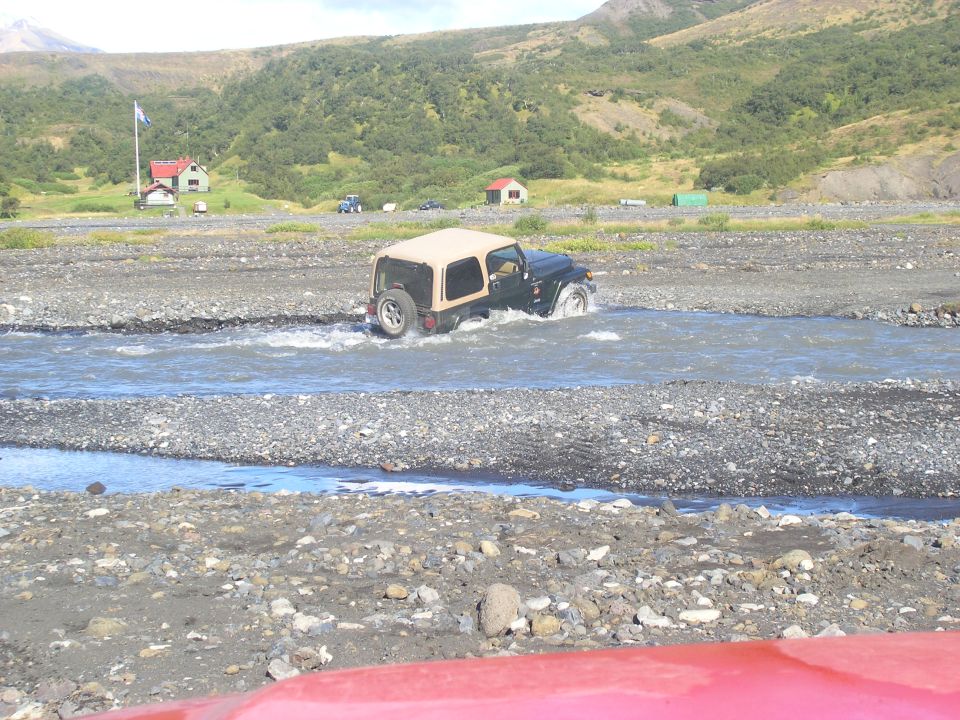 Jeep TJ driving through a rocky stream with a tan soft top