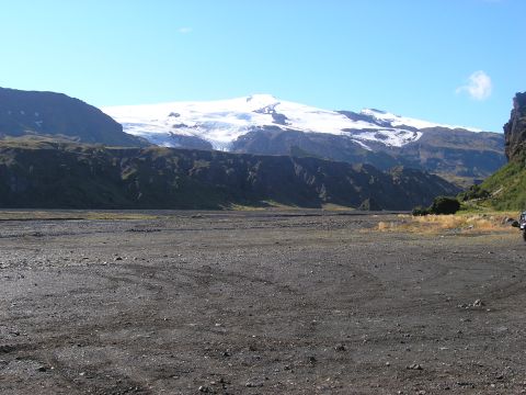 2001 Jeep Wrangler - A vehicle is parked in a vast, rocky terrain with a snow-covered mountain dominating the horizon under a clear blue sky.