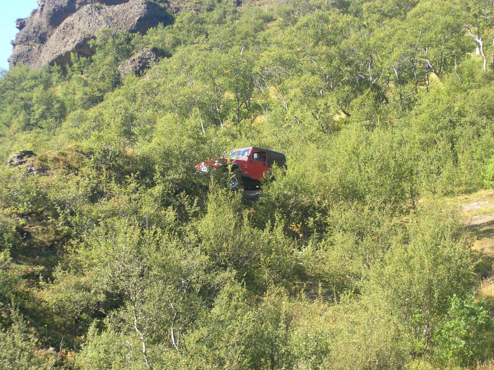 Red 2001 Jeep TJ on a grassy hill