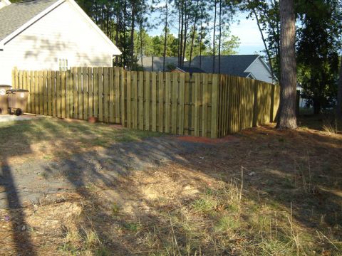 1986 Ford Bronco - A wooden privacy fence encloses a residential yard, with houses and trees visible in the background.