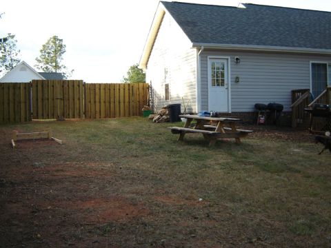 1986 Ford Bronco - A backyard scene with a wooden fence, picnic table, and a house in the background.
