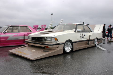 1991 Ford Bronco - Customized sedan with "Sexy CROWN" text and a prominent wide body kit is parked next to a pink sedan.