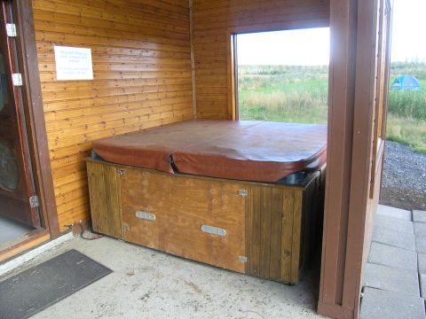 2001 Jeep Wrangler - A hot tub is housed within a wooden structure, offering a view of a rural landscape with a tent in the distance.