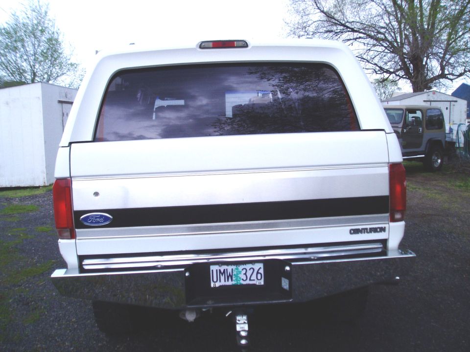 Rear of white Ford Centurion SUV conversion with Oregon plate UMW 326 in gravel lot