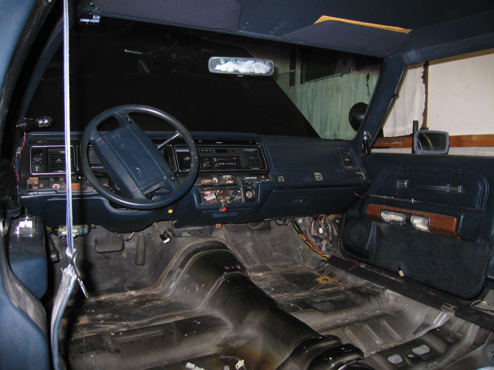 Gutted car interior with bare floor pan, dashboard, and steering wheel